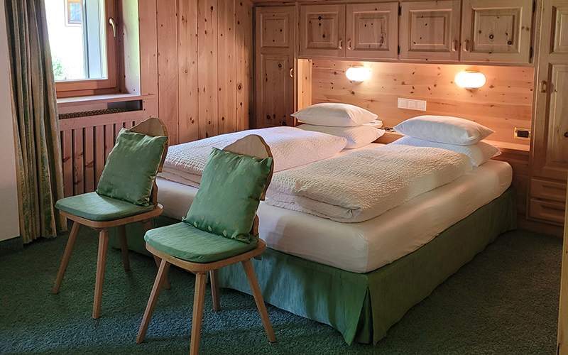 Double room at Garni Royal in Arabba, with single beds, Swiss pine wood furniture, and green armchairs.