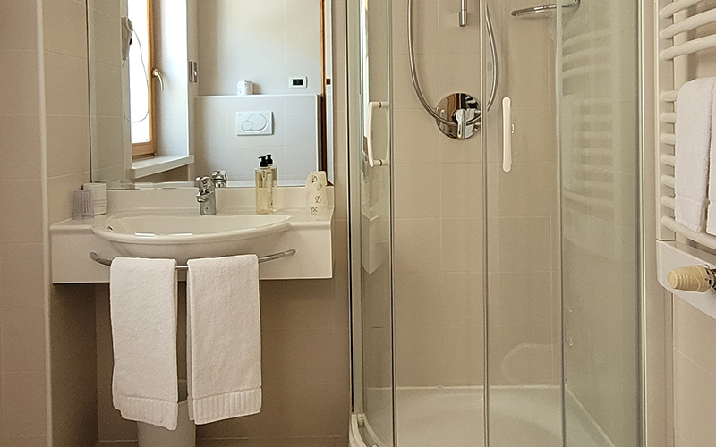 Modern and bright bathroom at Garni Royal with sink, mirror, shower, and heated towel rail with towels.