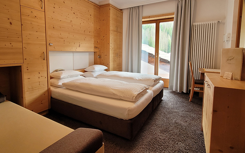 Swiss pine double room at Garni Royal in Arabba, with an extra bed, balcony, and Dolomite view.