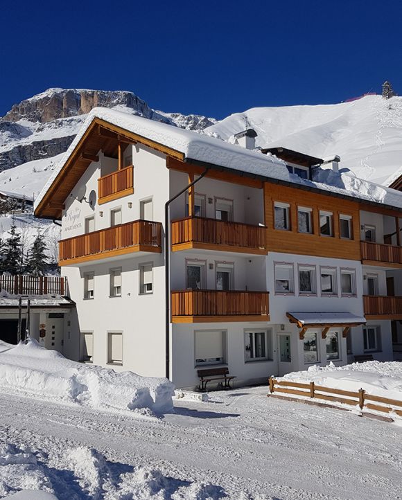 Appartamenti Alpenroyal ad Arabba in inverno, con neve fresca e le Dolomiti sullo sfondo.