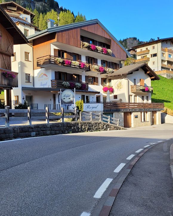Facciata del Garni Royal ad Arabba, con balconi fioriti e insegna, immerso nelle Dolomiti.